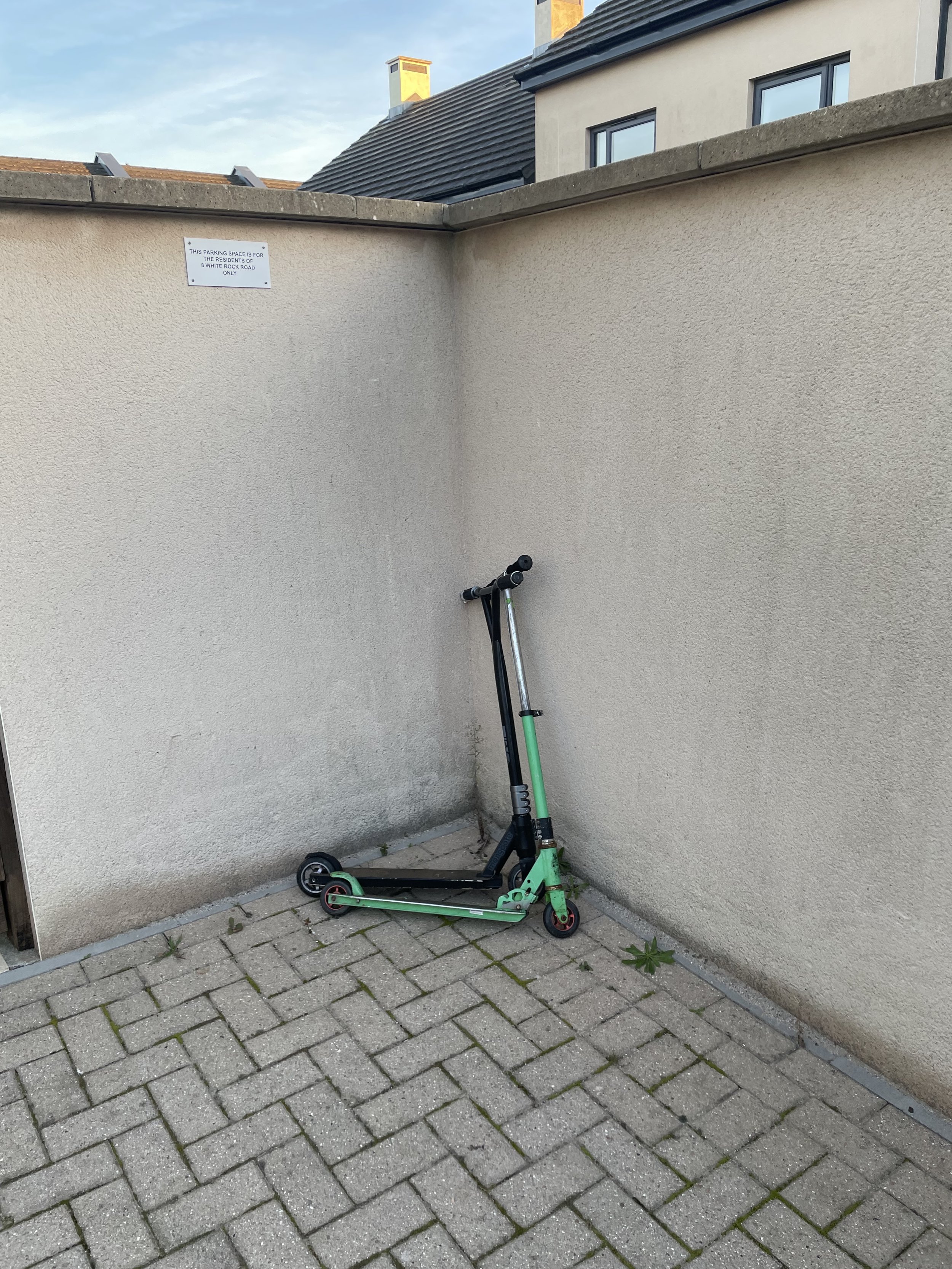 Two scooters left leaning against the wall — one slightly larger than the other