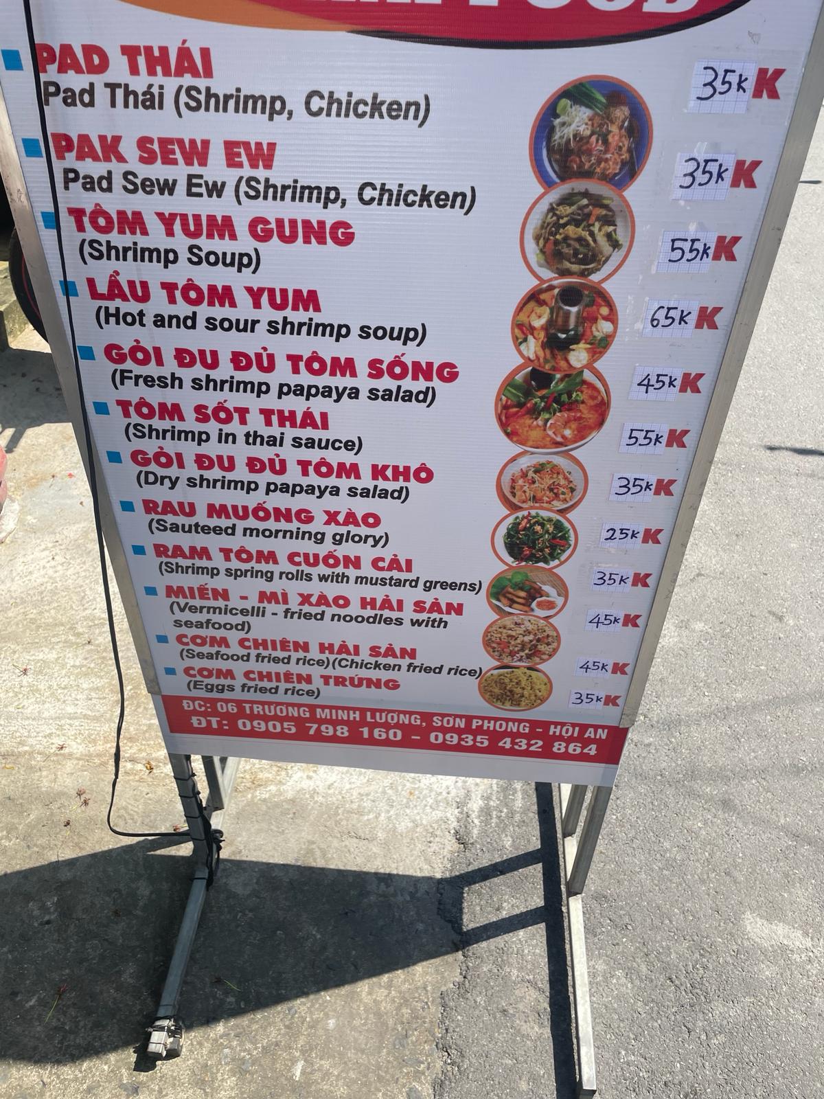 A roadside food cart menu listing Pad Thai, Tom Yum and other dishes