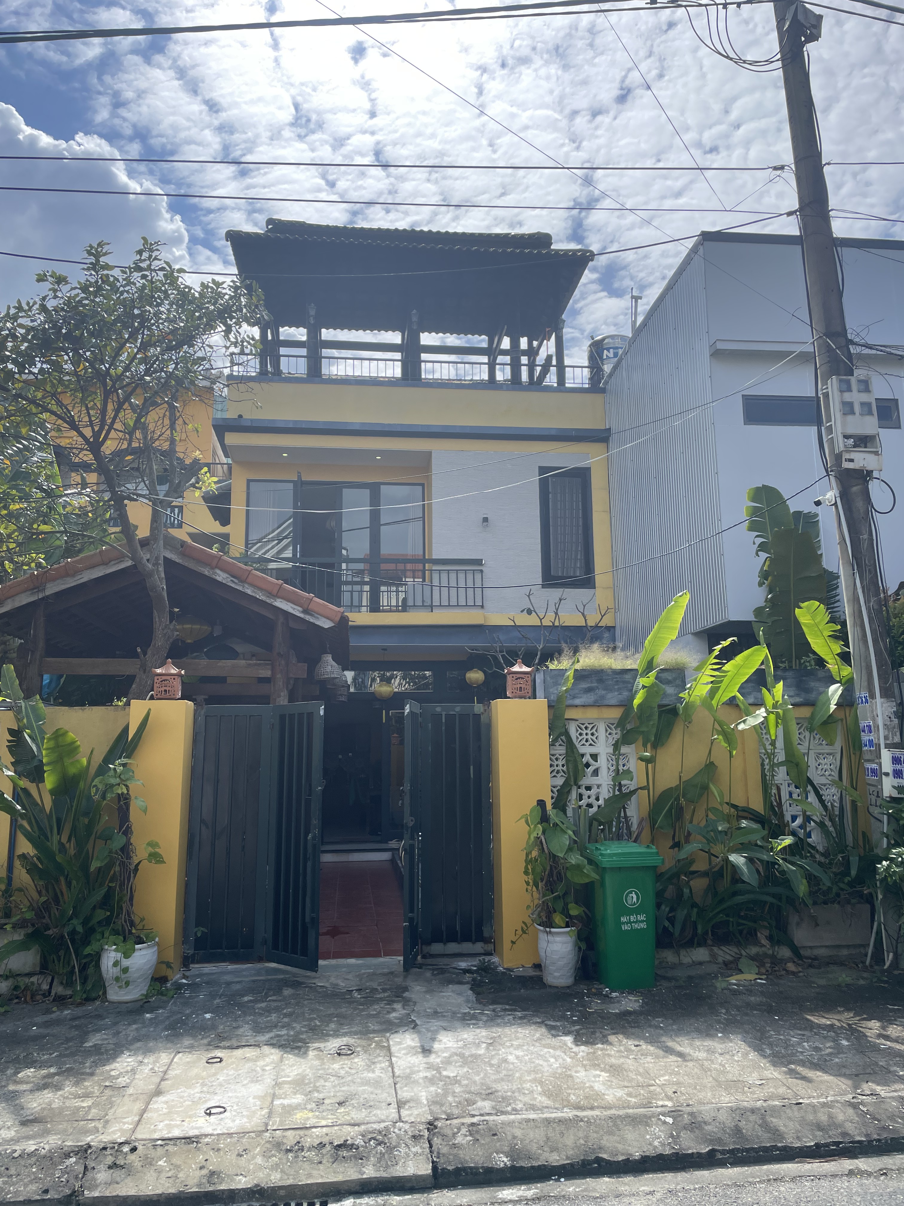 A larger yellow rental villa with a rooftop pavilion terrace