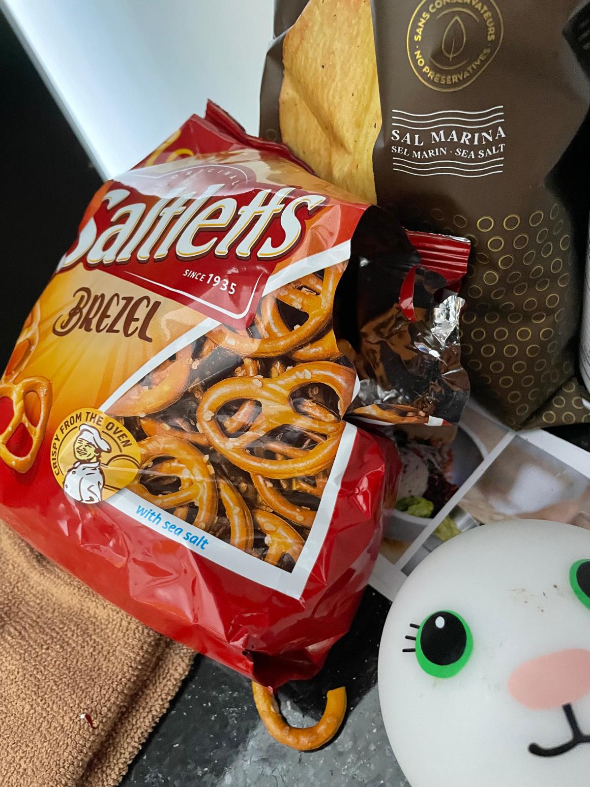 A bag of pretzels next to a dark snack packet torn open